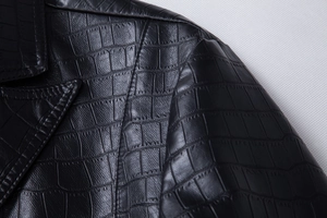 Macro shot of black crocodile embossed PU leather texture and stitching on jacket lapel