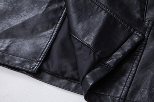 Close-up of black PU leather jacket hem with double stitching and fine grain texture