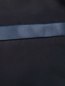 Dettaglio macro del tessuto twill nero con cuciture in ecopelle blu scuro grana litchi