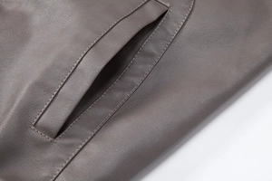 Close-up of the welt pocket and fine stitching on a dark faux leather motorcycle jacket