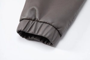 Macro detail of dark brown faux leather jacket sleeve with elastic cuff and pebbled texture