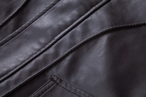 Macro view of textured dark brown PU leather jacket with precision double stitching details