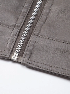 Macro detail of the grey leather jacket's fine texture, double stitching and metal zipper