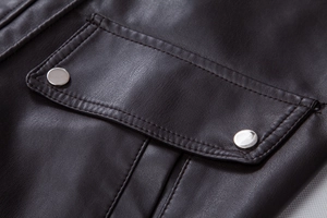 Detail of dark brown leather jacket pocket with silver snap buttons and textured stitching