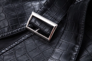 Detailed close-up of black crocodile embossed faux leather texture and silver belt buckle