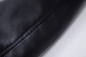 Close-up of black litchi grain PU leather jacket detail with precise double stitching