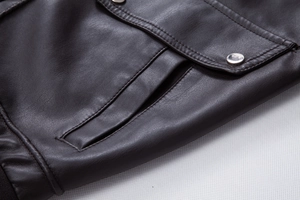 Close-up of deep brown leather jacket featuring metal snap button pocket and fine stitching