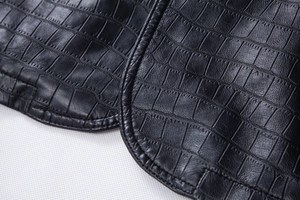 Close-up of black faux leather motorcycle jacket showing crocodile texture and stitching