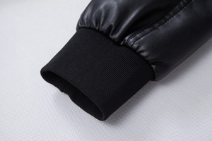 Detail of black faux leather jacket sleeve featuring a ribbed knit cuff and fine stitching