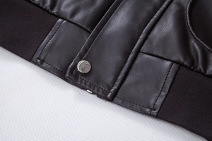 Close-up of leather jacket texture with silver snap button and ribbed knit cuff detailing