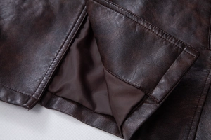 Detailed close-up of double stitching and silk lining on a brown PU leather jacket
