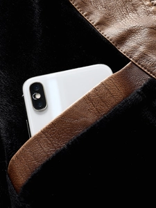 Macro view of leather jacket pocket with plush lining and a phone for scale