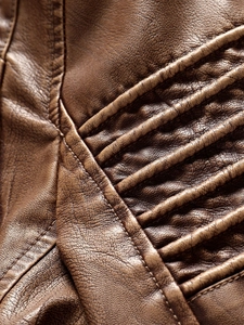 Close-up of brown PU leather jacket showing grain texture and parallel stitching detail