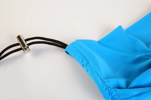 Macro shot of blue breathable fabric with black drawstring and silver metal spring toggle