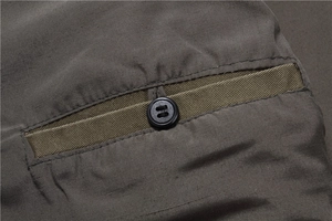 Close-up of horizontal pocket with black button on textured cotton vest fabric