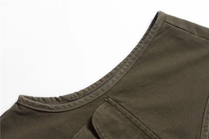 Detailed close-up of collar and multi-pocket stitching on men's olive green canvas vest