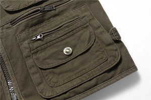 Detailed close-up of army green utility vest showing metal buckles and canvas pockets