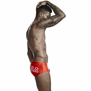 Detail of red men's square-cut swim trunks with side white letter print and elastic waistband