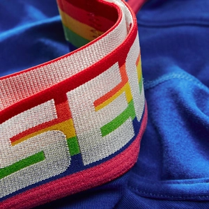 Close-up of blue men's briefs with rainbow elastic waistband and jacquard lettering
