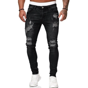 Dettaglio ravvicinato di jeans skinny neri da uomo con strappi alla moda e dettagli invecchiati