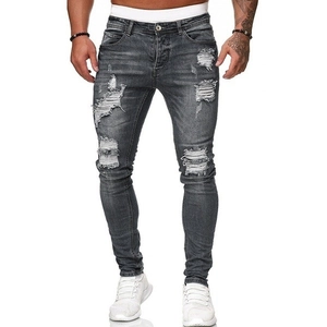 Dettaglio dei fori usurati e strappati su jeans neri slim fit da uomo lavati