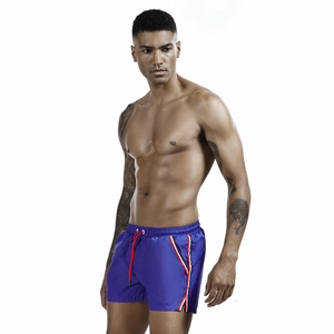 Detail of royal blue men's swim shorts featuring side stripes and a red drawstring waist