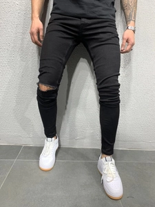 Détail du genou déchiré sur un jean en denim noir ajusté pour hommes de style urbain