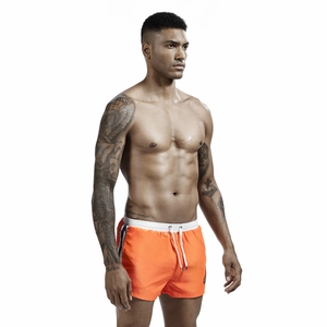 Detail of men's bright orange swim shorts with elastic drawstring and side stripes