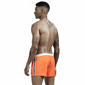 Detail of men's orange swim shorts featuring elastic waistband and side sport stripes