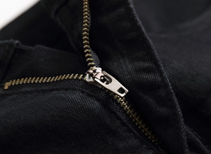 Close-up of durable metal zipper fly on black embroidered denim pants for men