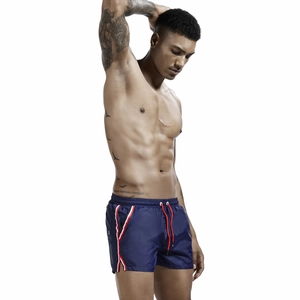 Detail of navy quick-dry swim trunks with red drawstring and side stripes for men