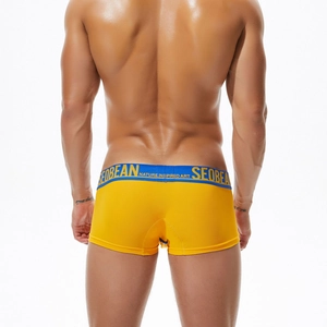 Macro detail of men's breathable yellow mesh boxer briefs with navy elastic waistband