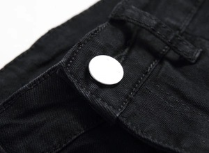 Detail view of high-density black denim fabric with a polished silver metal button