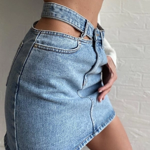 Détail d'une mini-jupe en jean bleu clair avec une taille haute ajourée unique au design