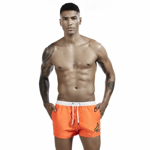 Close-up of bright orange men's athletic shorts featuring banana embroidery patch details