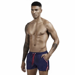 Detail of navy swim shorts featuring red drawstring and contrast striped pocket trim