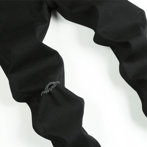 Gros plan du détail genou déchiré avec bords effilochés sur jean skinny noir