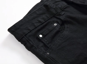 Detailed macro view of black denim jeans front pocket with metallic rivets and stitching