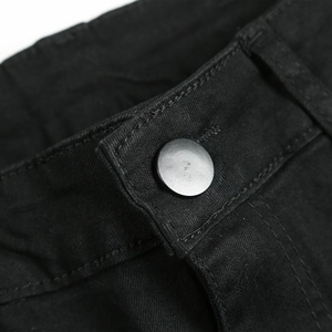 Détail du bouton en métal noir mat et texture sergé sur un jean noir ajusté pour homme