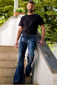 Detail of vintage blue flare jeans with whiskered textures on the thighs for men