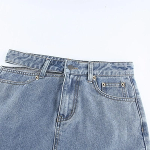 Détail de la taille d'une jupe en jean bleu clair avec découpes latérales et boutons argent