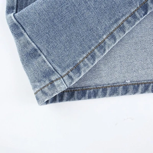 Détail du tissu denim bleu clair avec double couture orange et texture en sergé