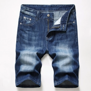 Detail view of mid-blue denim shorts with vintage wash and whiskers on white background