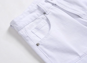 Détail de la taille d'un jean blanc avec poches et rivets métalliques argentés polis
