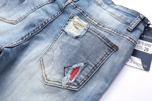 Detail of distressed light blue denim with vintage wash and unique ripped back pockets