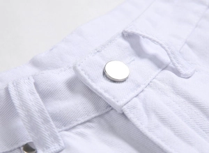 Détail d'un jean blanc montrant un bouton en métal poli et des coutures renforcées