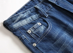 Detail of dark blue denim jeans waist with metal rivets and distressed vintage texture