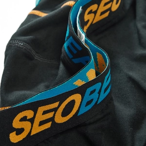 Macro shot of men's boxer briefs showing the wide elastic waistband and orange stitching