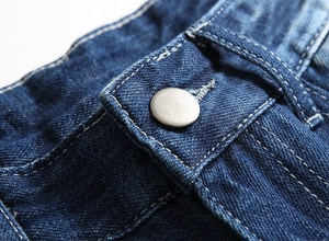 Detail of dark blue denim waist with silver matte button and white contrast stitching
