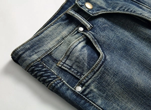 Détail d'un jean vintage avec délavage moustaches, rivets métalliques et couture de qualité
